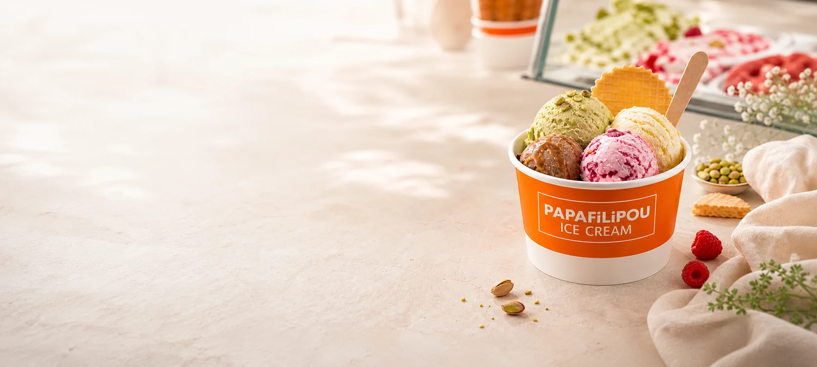 Branded PapaFilipou ice cream cup with colourful scoops on a light cafe table
